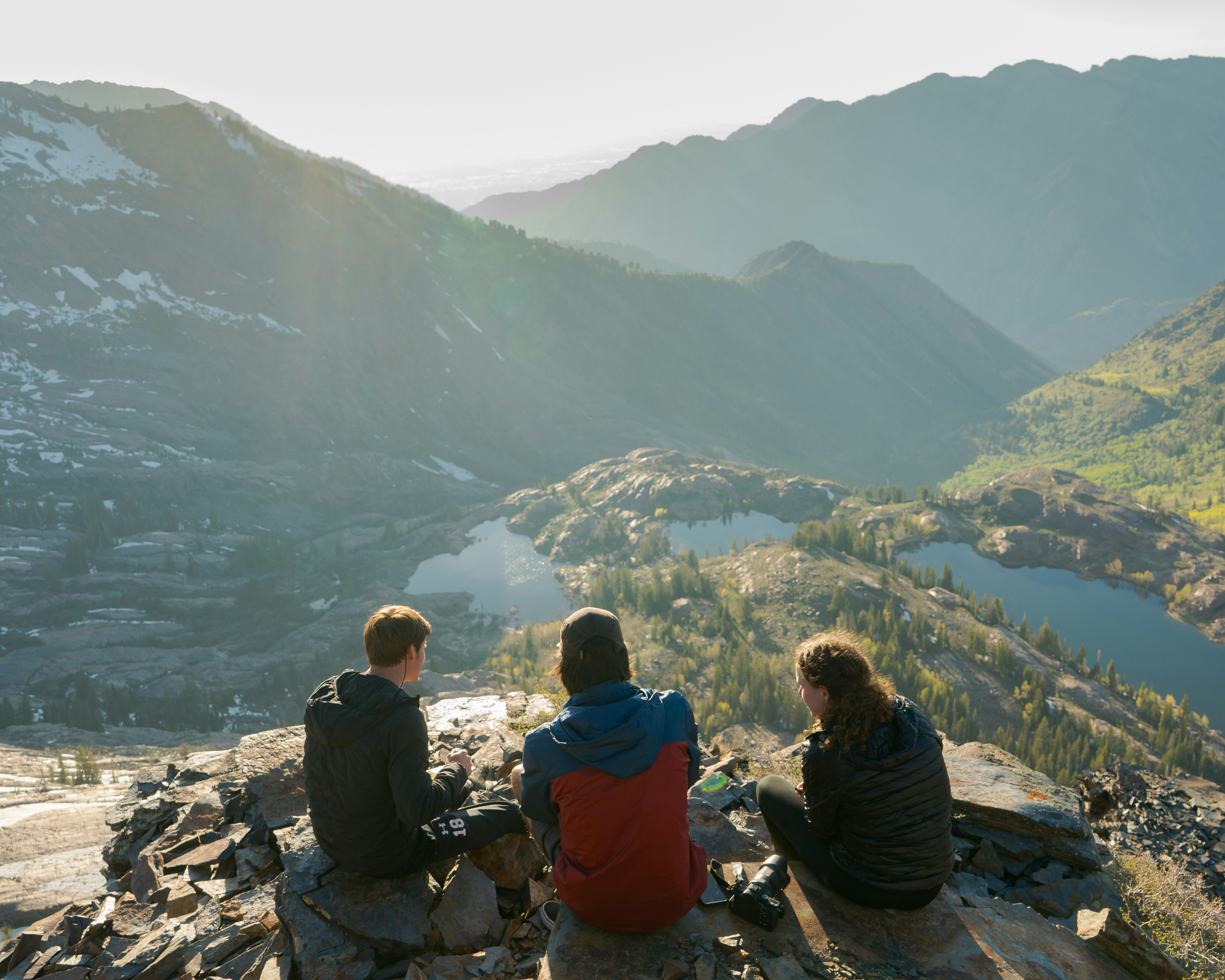 Friends sitting together on a mountain summit, looking out over the landscape